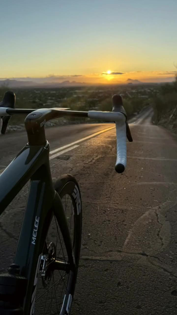 Riding view over the handlebars, desert road ahead, low sun on the horizon.
